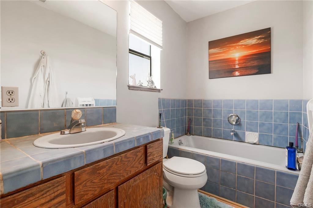 bathroom with blue tiled vanity, bathtub and white toilet