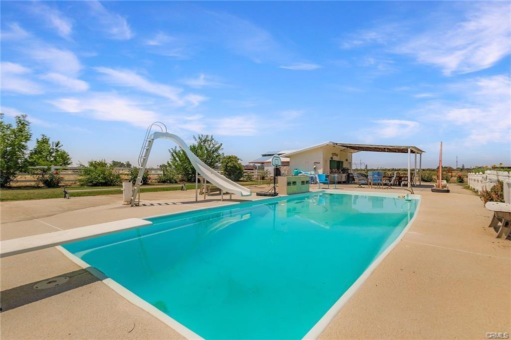Large pool with slide, diving board and out building with concrete patio