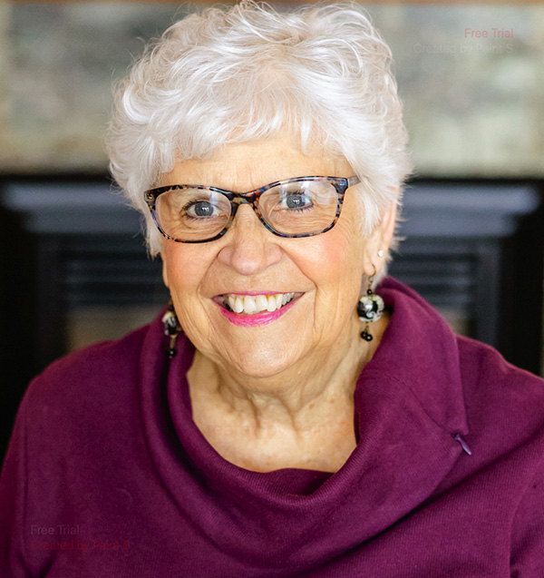 Joann smiling wearing glasses, earings, and a purple cowell neck sweater